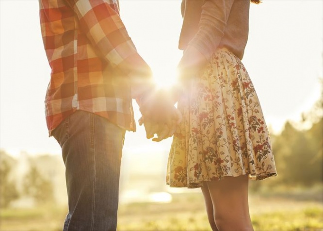 Young couple in love walking in the autumn park holding hands looking in the sunset