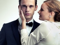 A cropped studio portrait of a dapper young man with a beautiful girl on his arm