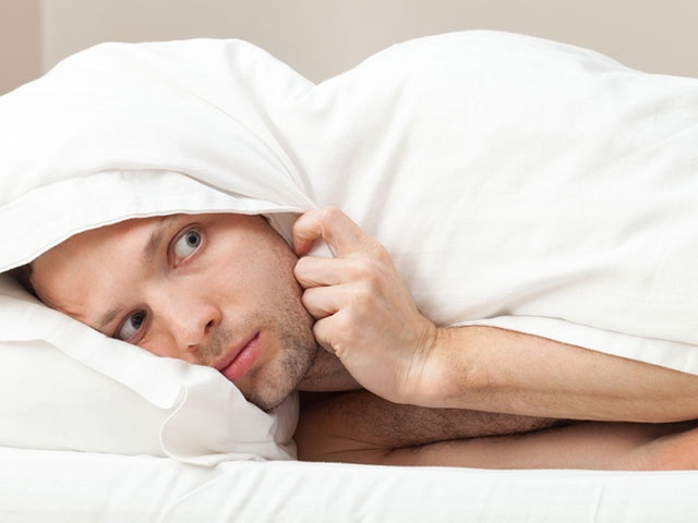 Portrait of funny scared Young Caucasian man in bed
