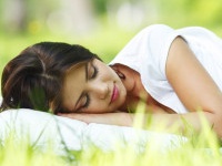 Young woman sleeping on soft pillow in fresh spring grass