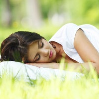 Young woman sleeping on soft pillow in fresh spring grass