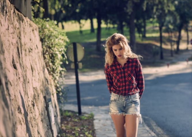 Beautiful woman with long blond curly hair. Woman in checkered shirt and blue jeans