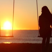 Single woman alone swinging on the beach