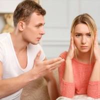 Bad time. Young frowning woman covering her ears while boyfriend is explaining something to her.