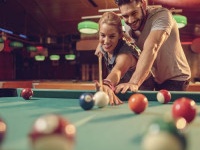 Happy couple having fun while playing snooker in a pool hall.