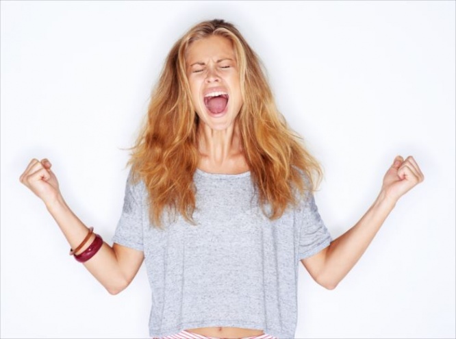 A pretty young girl yelling out in frustration with her fists raised - white background