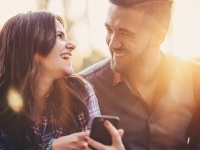 Happy young people with phone texting outdoors