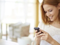 Image of young female reading sms on the phone in cafe