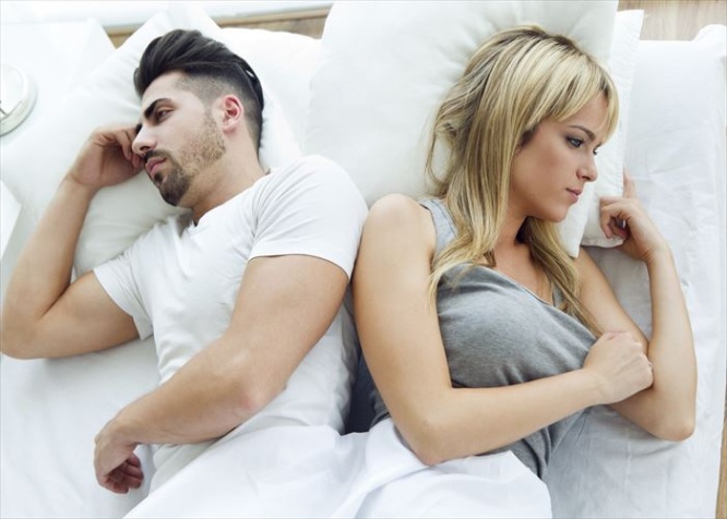 Portrait of upset couple lying back to back in bed