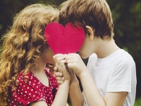 Cute children holding red heart shape in summer park. Valentines day background.