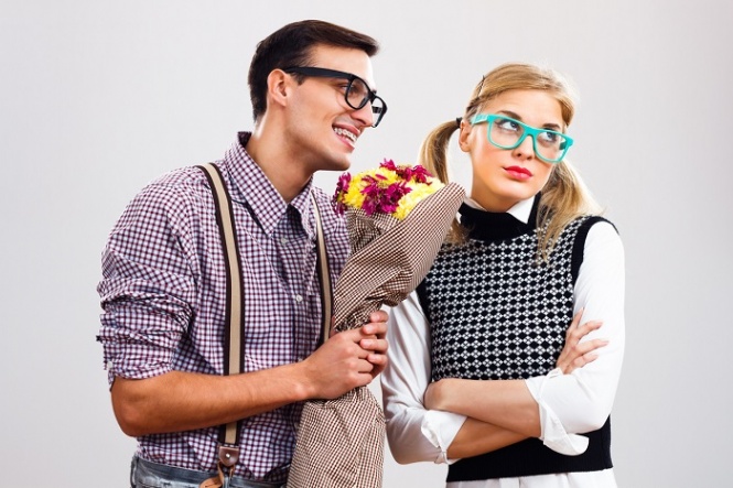 Nerdy man is giving a bouquet of flowers to his girlfriend,he had made a mistake and he is hoping that she will forgive him.