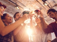 Low angle view of happy start up team toasting with wine while celebrating their business achievement.