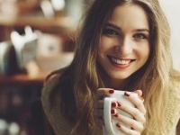 charming girl drinking cappuccino and eating cheesecake in coffee shop