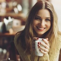 charming girl drinking cappuccino and eating cheesecake in coffee shop