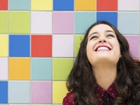 Happy girl laughing against a colorful tiles background. Concept of joy