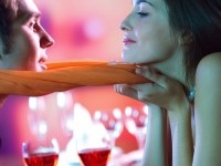 Young attractive happy couple kissing in restaurant, celebrating or on romantic date