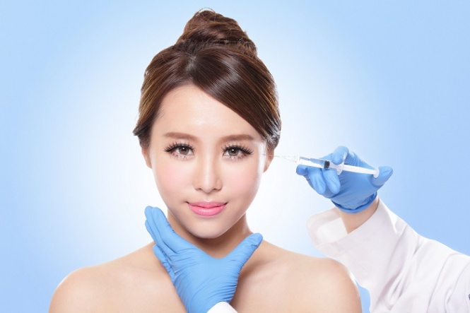 Close up of cosmetic injection to the pretty woman face. Isolated on blue background, asian