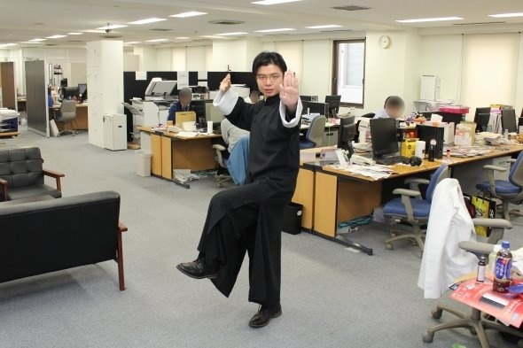 職場でノリノリでポーズを取るT編集長。最初のころは笑っていた隣のニュース編集部も、途中から放ったらかしで仕事に集中している