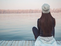 Girl sitting on pier and lookingat the river