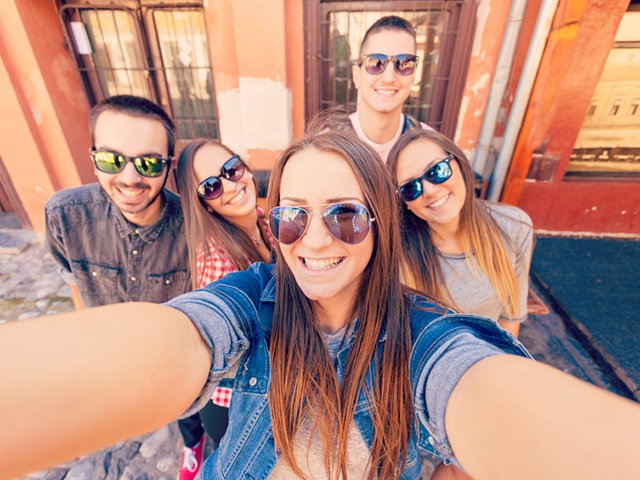 Young friends laughing and taking selfie