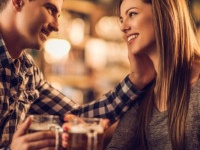 Loving young couple talking to each other in a bar and drinking beer in a pub.