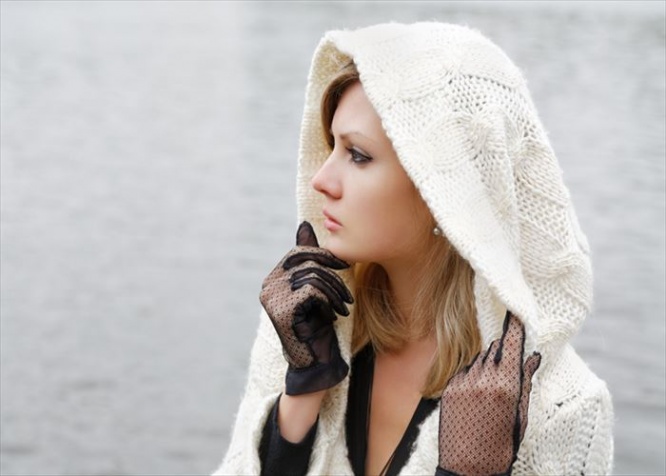 The thoughtful girl in  knitted dress on a background of water