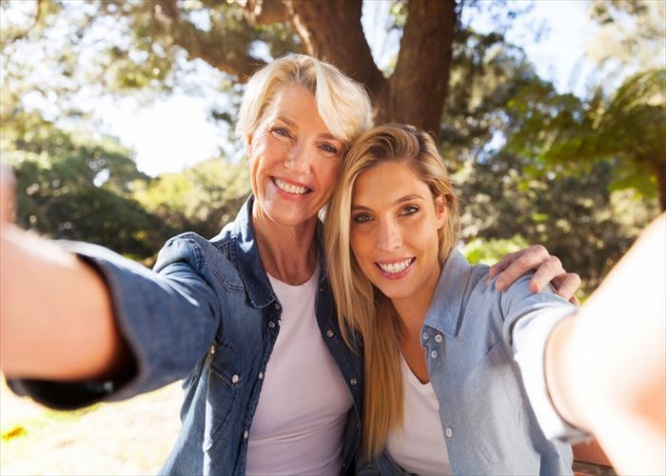 happy senior woman and daughter taking selfie together