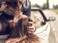 Young loving couple having a desire toward each other while lying on cabriolet.