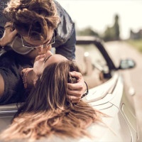 Young loving couple having a desire toward each other while lying on cabriolet.