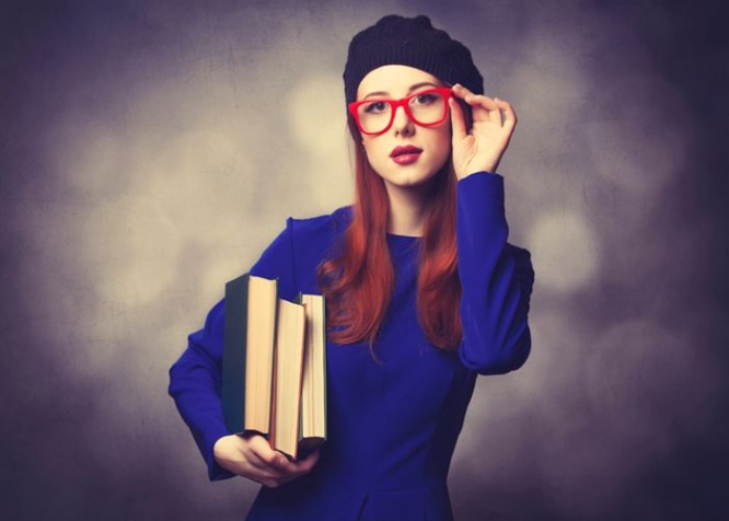 Portrait of beautiful girl in blue dress with books and bokeh on background.
