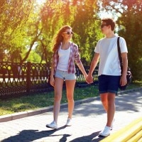 Summer, vacation, fun, relationships and people concept - pretty modern young couple in love walking in sunny summer day