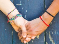 Two women holding hands with a wooden background. One is caucasian, the other is black. Multicultural, homosexual love and friendship concepts.