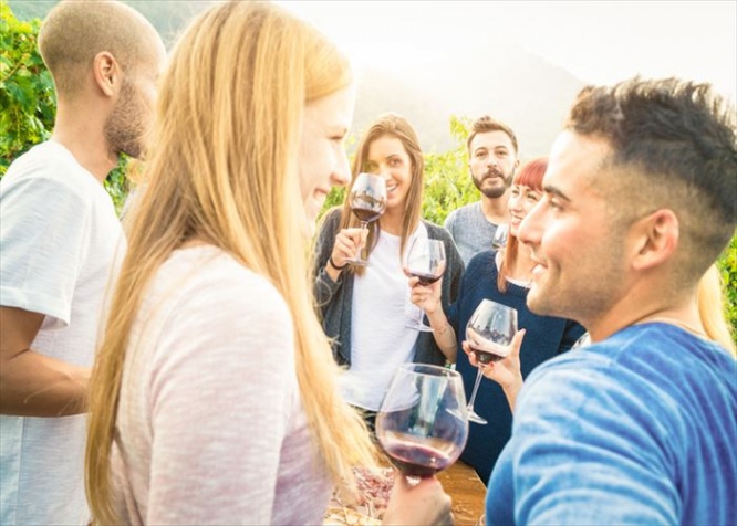 Happy friends having fun and drinking wine - Friendship concept with young people enjoying harvest time together at farmhouse vineyard countryside - Bright desat filter with focus on background faces