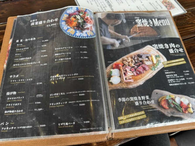 Two-page restaurant menu spread with Japanese text and prices on a dark glossy background.
