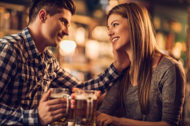 Loving young couple talking to each other in a bar and drinking beer in a pub.