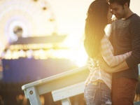 romantic couple kissing at sunset in front of santa monica ferris wheel.