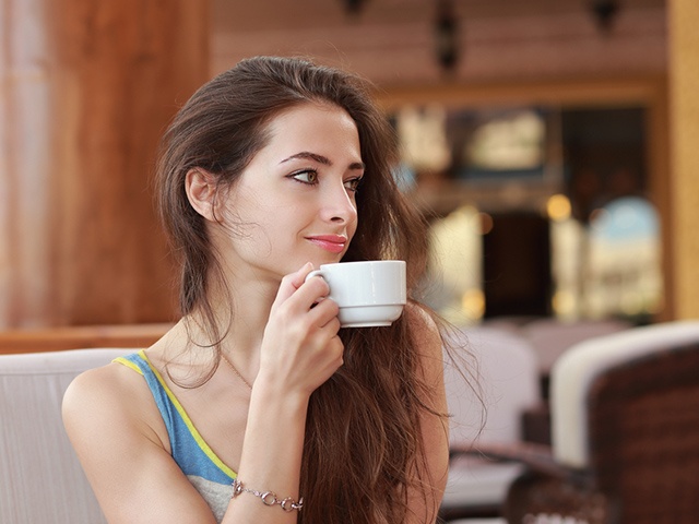 Woman with cup of coffee sitting in cafe and looking