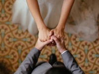 A close up shot of a bride and groom holding hands from a top view.