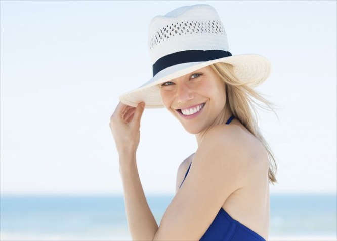 Woman wearing a straw hat and smiling. Portrait of a happy young woman in blue bikini with panama hat looking at camera with copy space.
