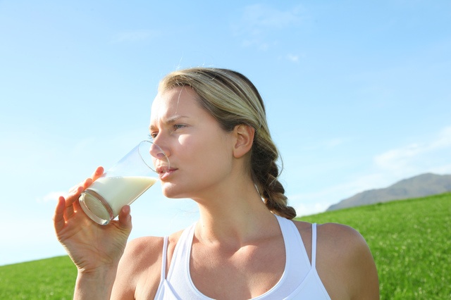 Beautiful blond woman drinking milk in countryside