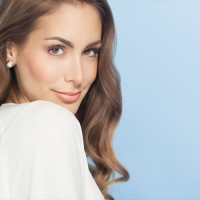 Young beautiful woman with long hair posing and smiling over blue background. Fashion and beauty concept in studio.