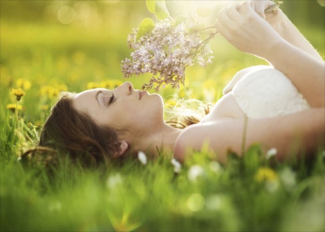 Beautiful girl is relaxing lying on grass in the garden
