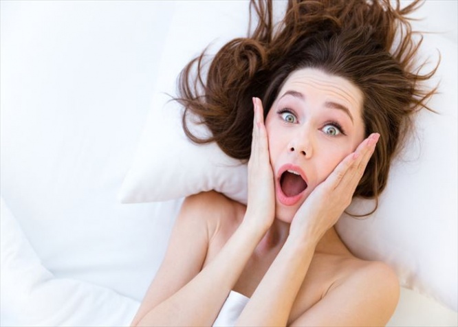Shocked astonished pretty young woman wake up late in white bed