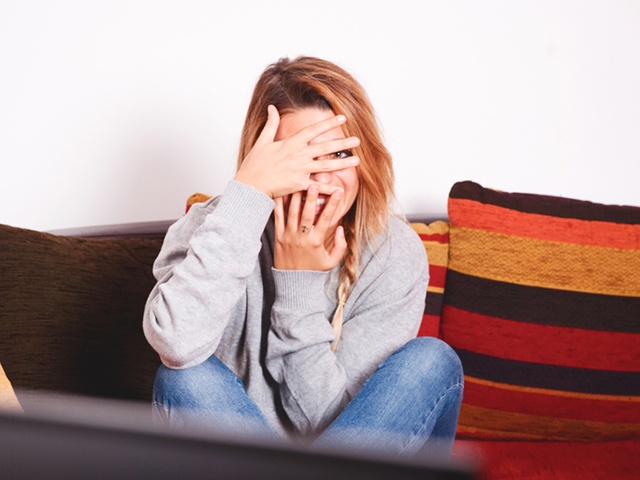 Girl covers her eyes in front of the tv