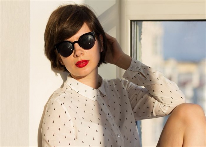 Girl with sunglasses daydreaming sitting by the window