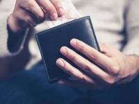 Closeup on a man's hands as he is getting a banknote out of his wallet