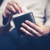 Closeup on a man's hands as he is getting a banknote out of his wallet