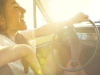 Happy young woman driving her car while out on a roadtrip