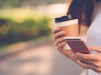 Close-up image of woman texting and drinking coffee outdoors