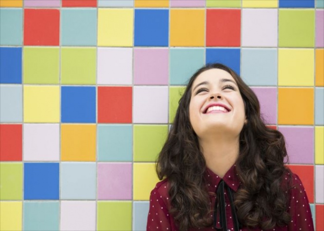 Happy girl laughing against a colorful tiles background. Concept of joy